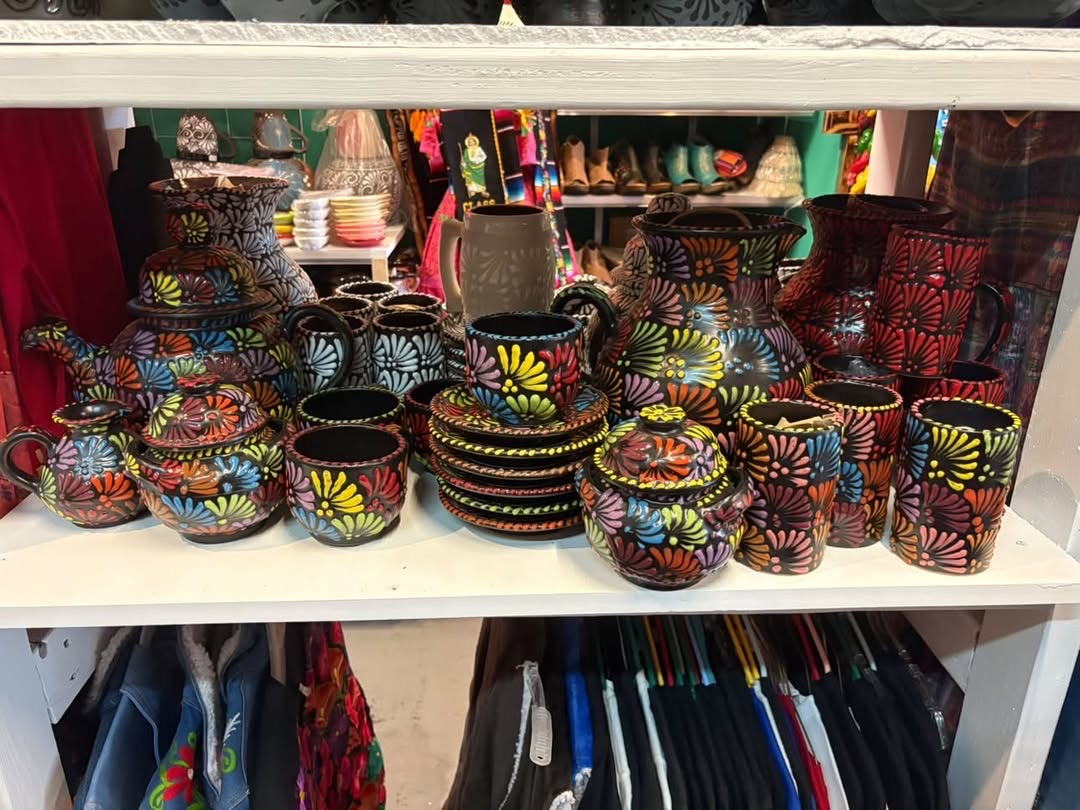 Bold black Talavera dinnerware with colorful floral patterns on a shelf